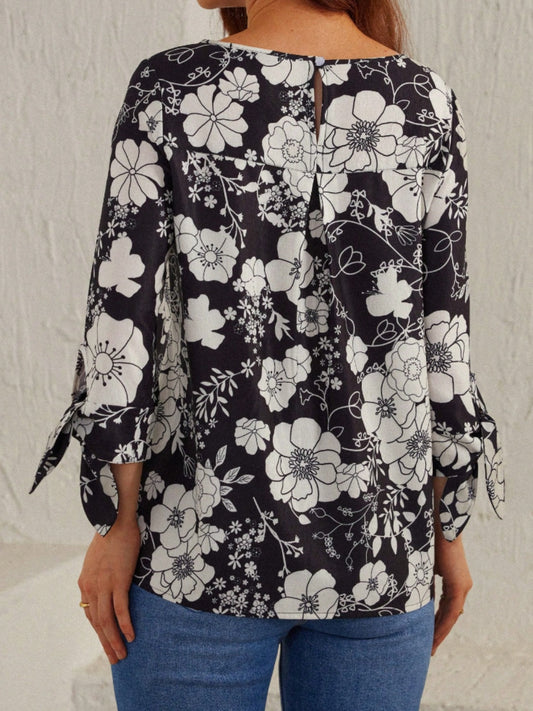 Women’s classic black and white floral blouse with tied sleeves for a feminine touch.