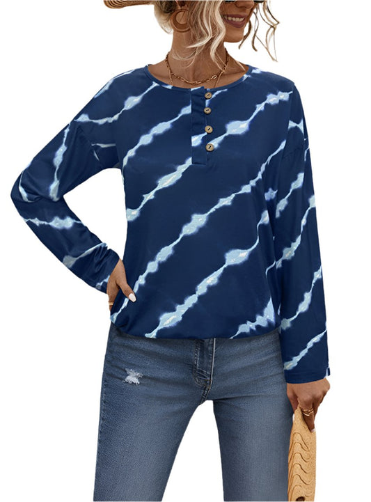 Woman wearing a blue tie-dye henley top with wooden-style buttons and long sleeves, paired with jeans.