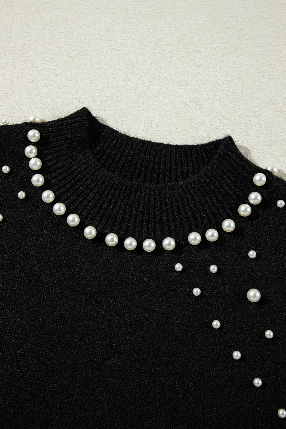 Soft black sweater with pearl embellishments for a sophisticated fall outfit.