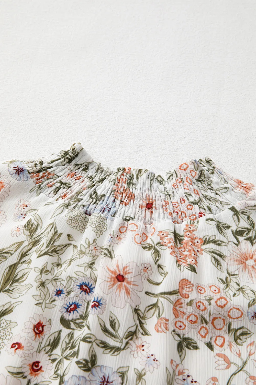 Close-up of the high neckline and floral print design on a flowy smock dress.