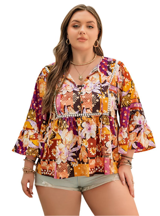 Woman wearing a vibrant floral patchwork blouse with 3/4 bell sleeves.