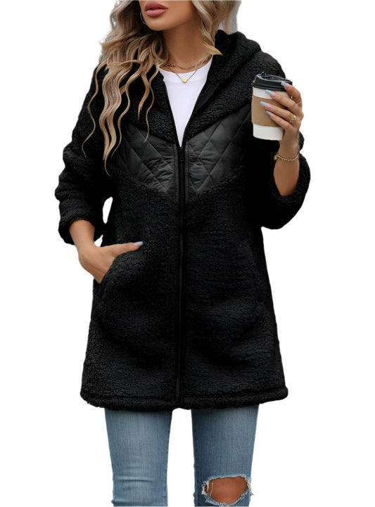Woman wearing a black fuzzy zip-up hooded jacket with quilted chest detailing.
