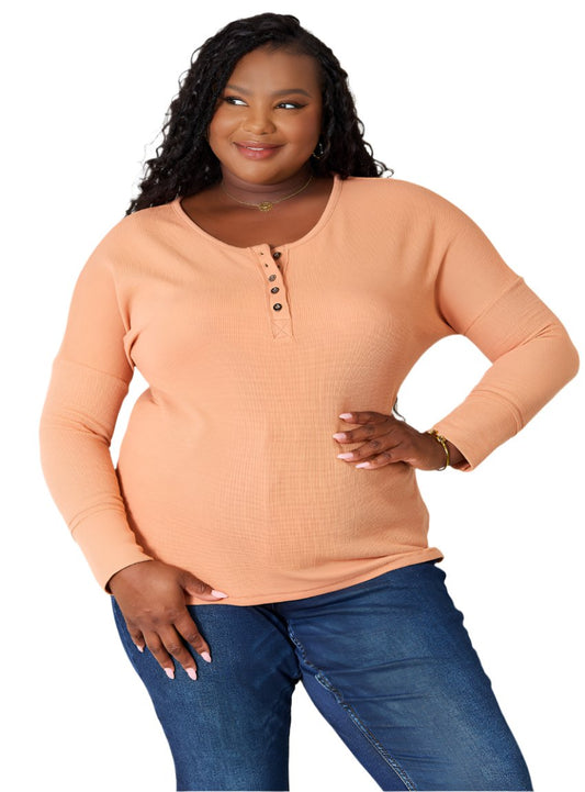 Front view of peach half-button long-sleeve top for women.