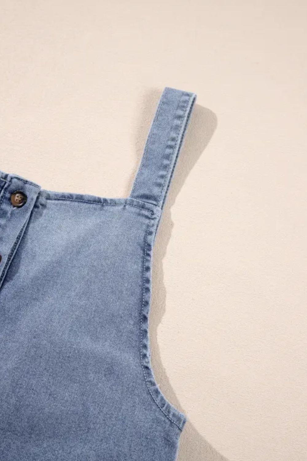 Close-up of denim overalls showcasing wide straps and buttons.