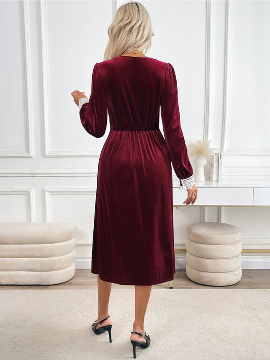 Back view of long sleeve ruched red midi dress with elegant lace accents.