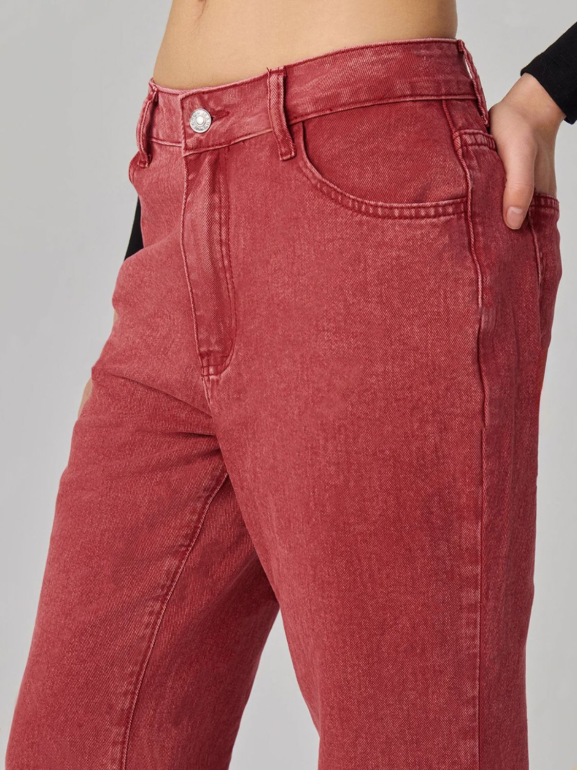 Closeup of red denim texture on vintage bootcut jeans highlighting fabric quality.