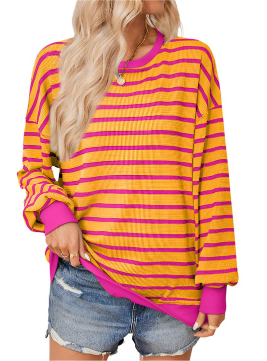 Orange striped oversized sweater styled casually with denim shorts.