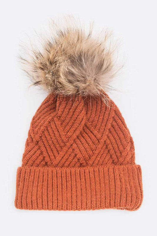 Rust-colored knit winter hat with faux fur pom detail