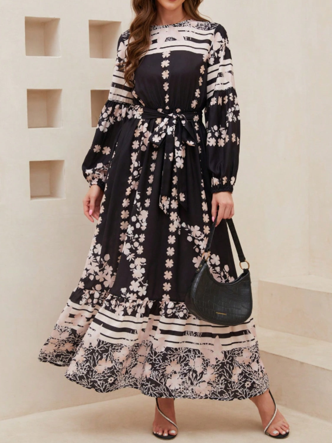 Elegant black maxi dress with beige floral print and flowy silhouette.