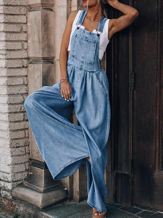 Relaxed-fit wide-leg denim overalls styled with a white tank top.