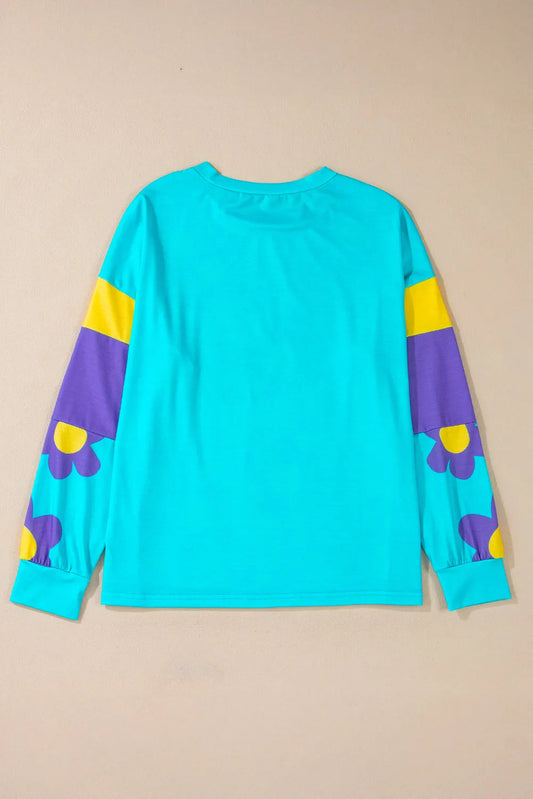 Teal floral print top with bold purple and yellow flowers, paired with casual denim shorts.