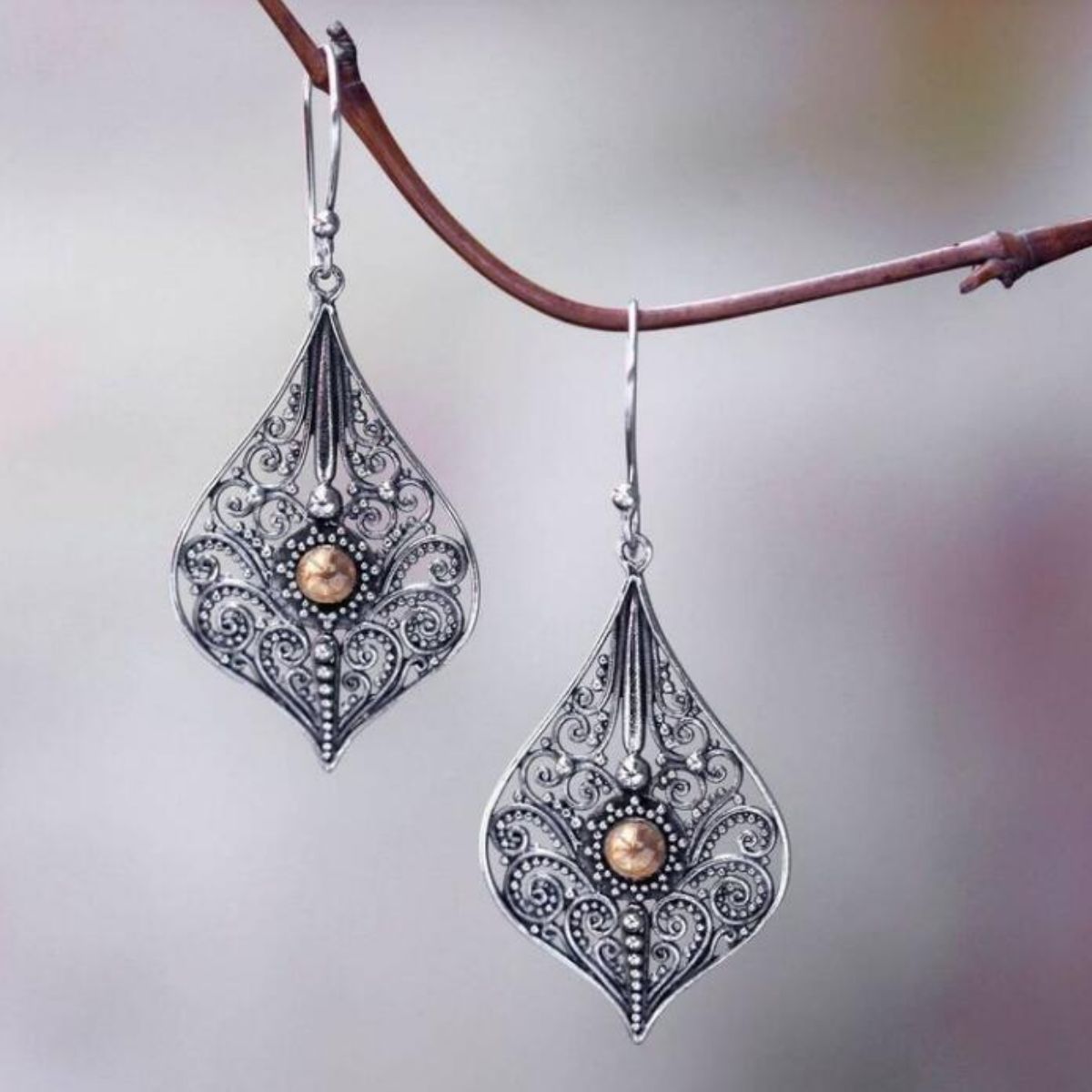 Teardrop earrings featuring a detailed filigree pattern and a central pearl bead