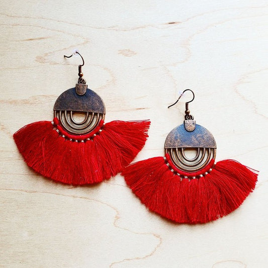 Red tassel earrings with rustic bronze accents on a wooden background.Bronze-tone half-moon earrings with vibrant red tassels, handcrafted for a boho-chic style.