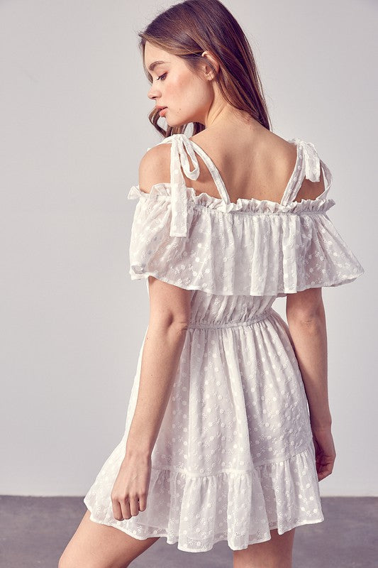 White summer dress featuring playful ruffles and tie shoulder straps.