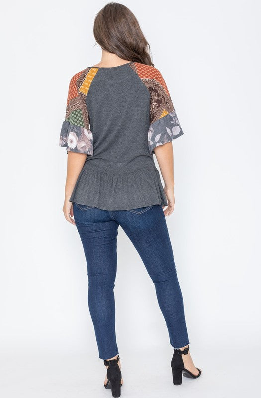 Charcoal gray top with a peplum hem and patchwork sleeves