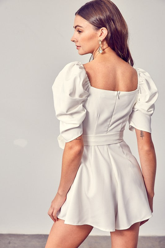 Sophisticated white romper with puffed sleeves and a wrap front.