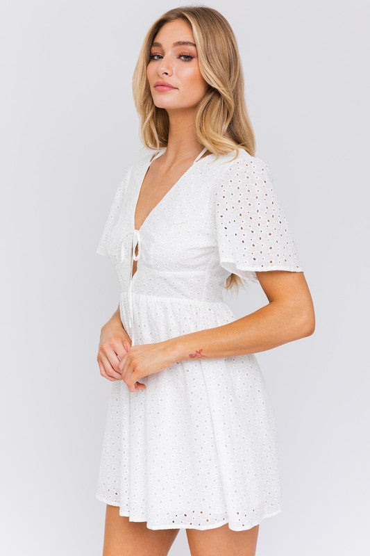 White eyelet dress featuring a front tie and flared design