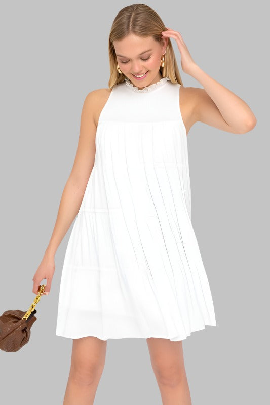 High-neck sleeveless white dress with ruffle detail and tiered skirt.