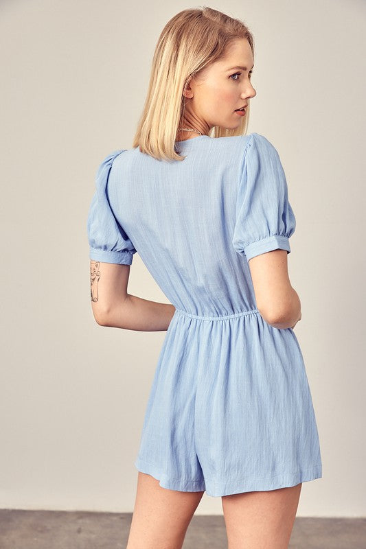 Chic light blue romper with bow tie and comfortable puff sleeves.