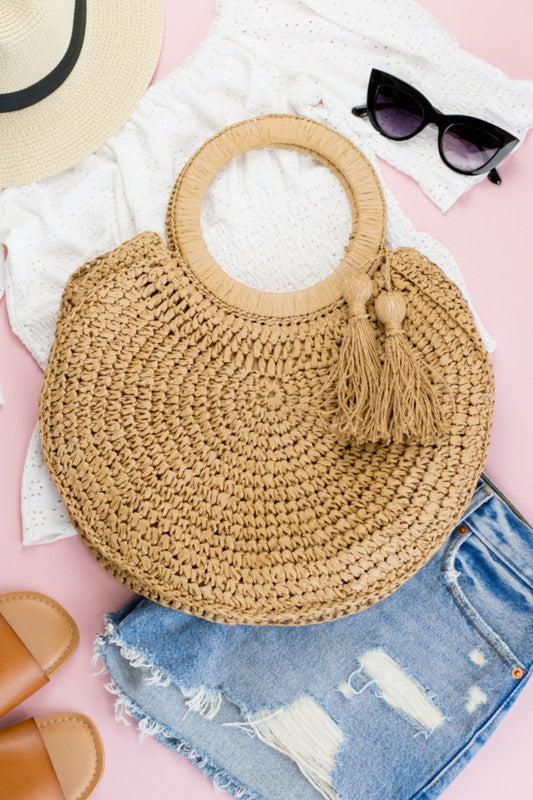 Woven straw tote bag with round handles and tassel accents.