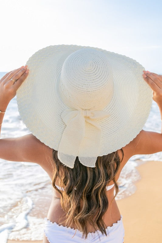 Woman enjoying a sunny day in a stylish wide brim straw hat with bow.