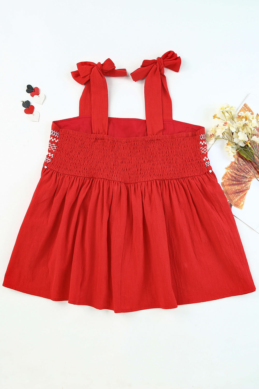 Red top featuring adjustable tie straps and embroidery.