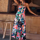 Woman wearing a floral maxi dress with a halter neck, standing on a beach.