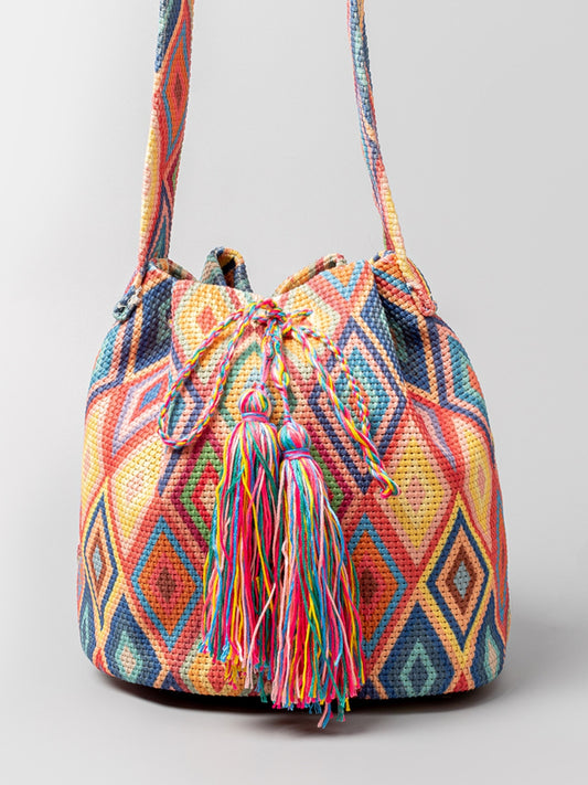 Multi-colored geometric patterned bucket bag with colorful tassels.