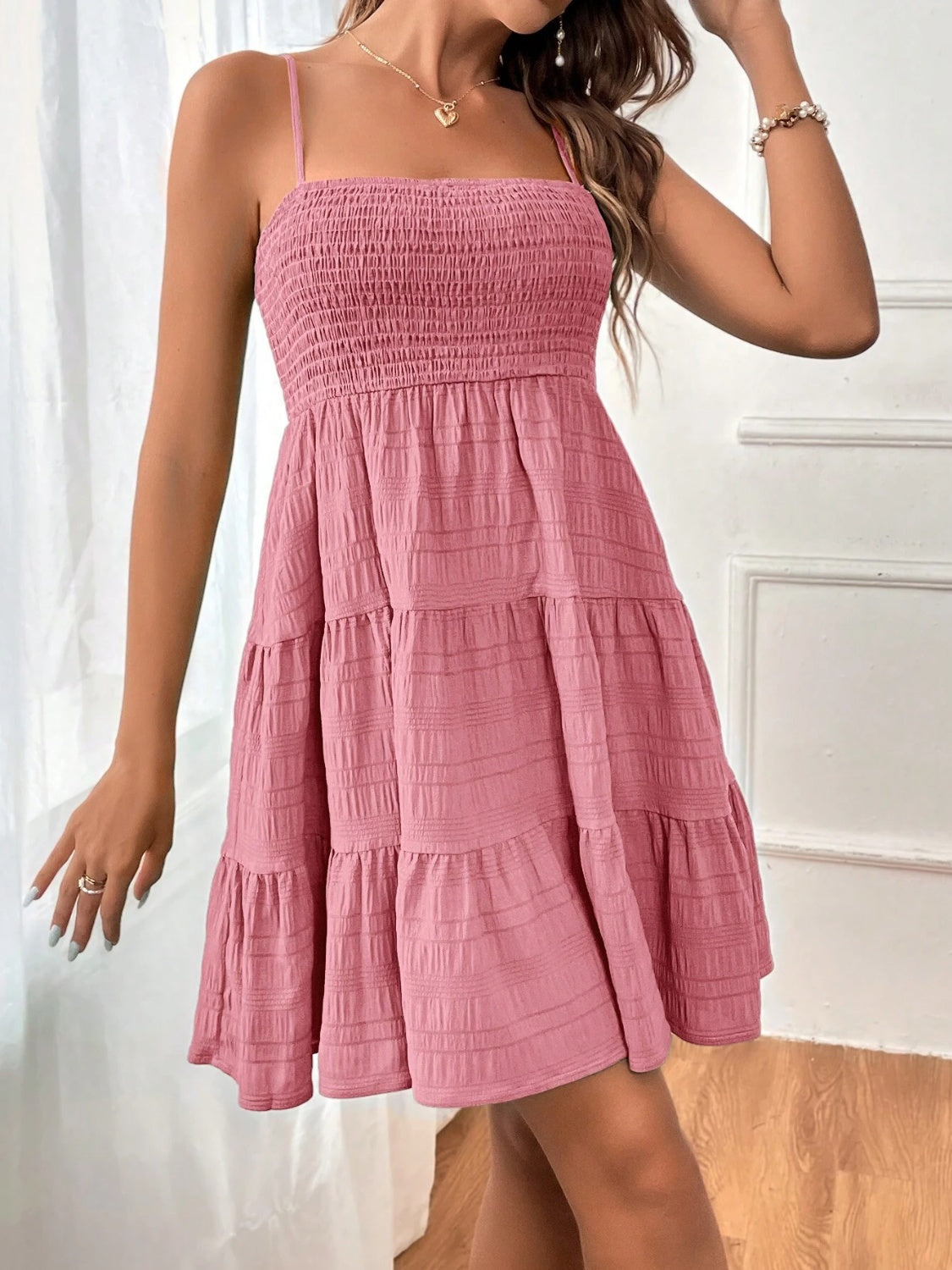 Chic sleeveless mini dress with a smocked bodice and tiered skirt, perfect for summer. Available in 8 colors for any occasion.