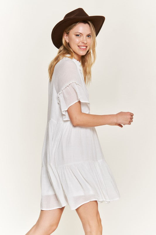 Casual white boho dress with a tiered design and ruffled sleeves.