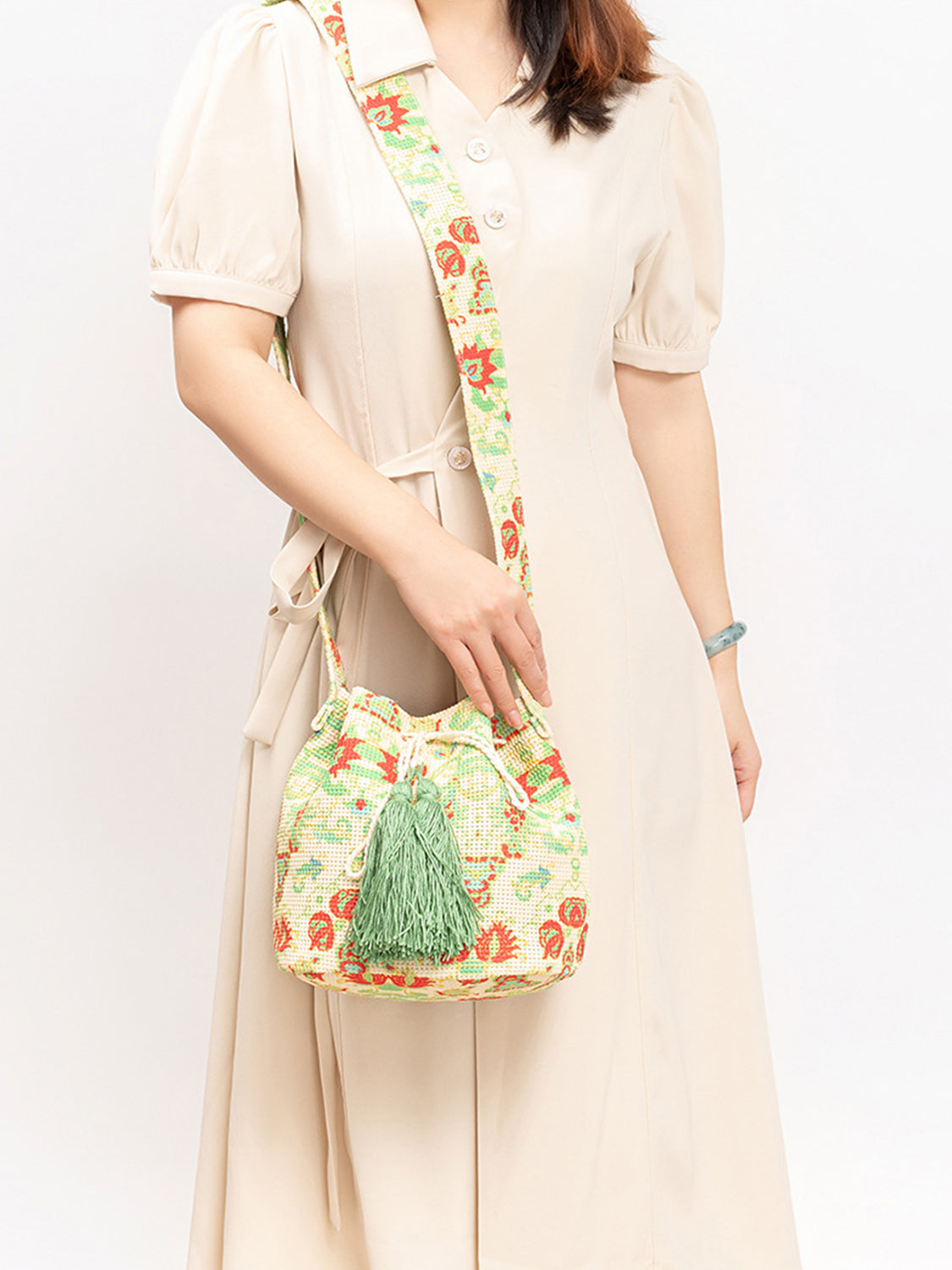 Green and cream patterned bucket bag with drawstring closure.