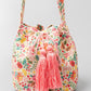 Pink floral bucket bag with large pink tassels.