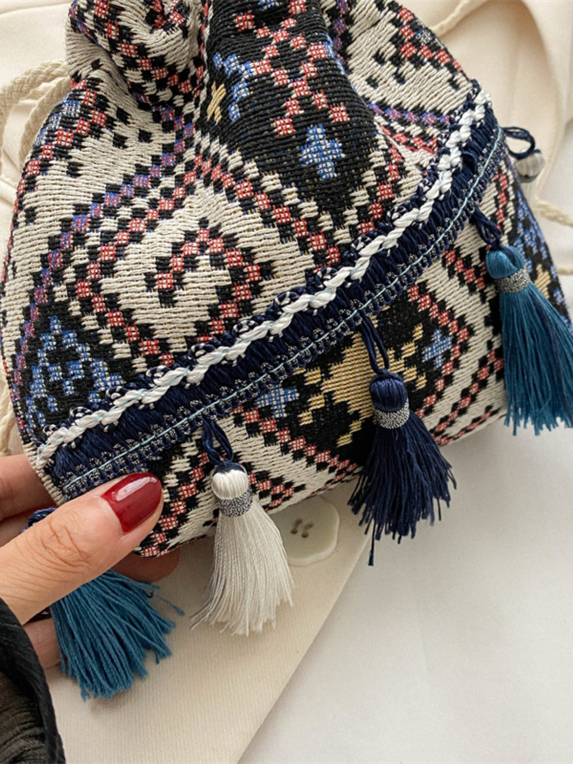 Black woven drawstring pouch bag featuring intricate geometric patterns and tassels.