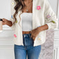 White cardigan with pink, yellow, purple, and blue flowers.