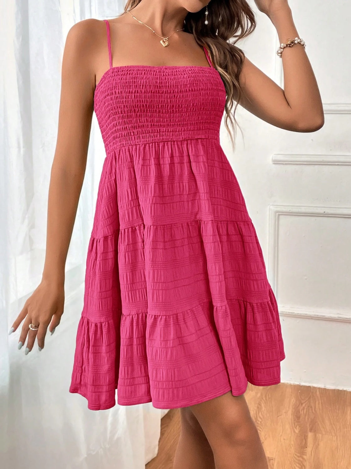 Chic sleeveless mini dress with a smocked bodice and tiered skirt, perfect for summer. Available in 8 colors for any occasion.
