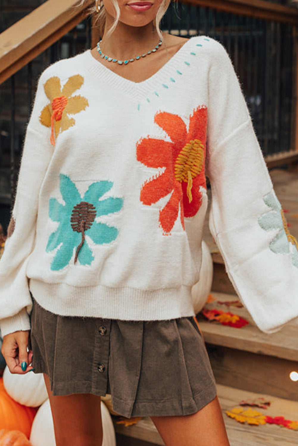 Retro 60s-inspired ivory knit sweater with colorful floral designs.
