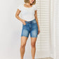 Elevate your summer wardrobe with Judy Blue's Double Button Bermuda Denim Shorts, offering tummy control for a sleek look and ultimate comfort.
