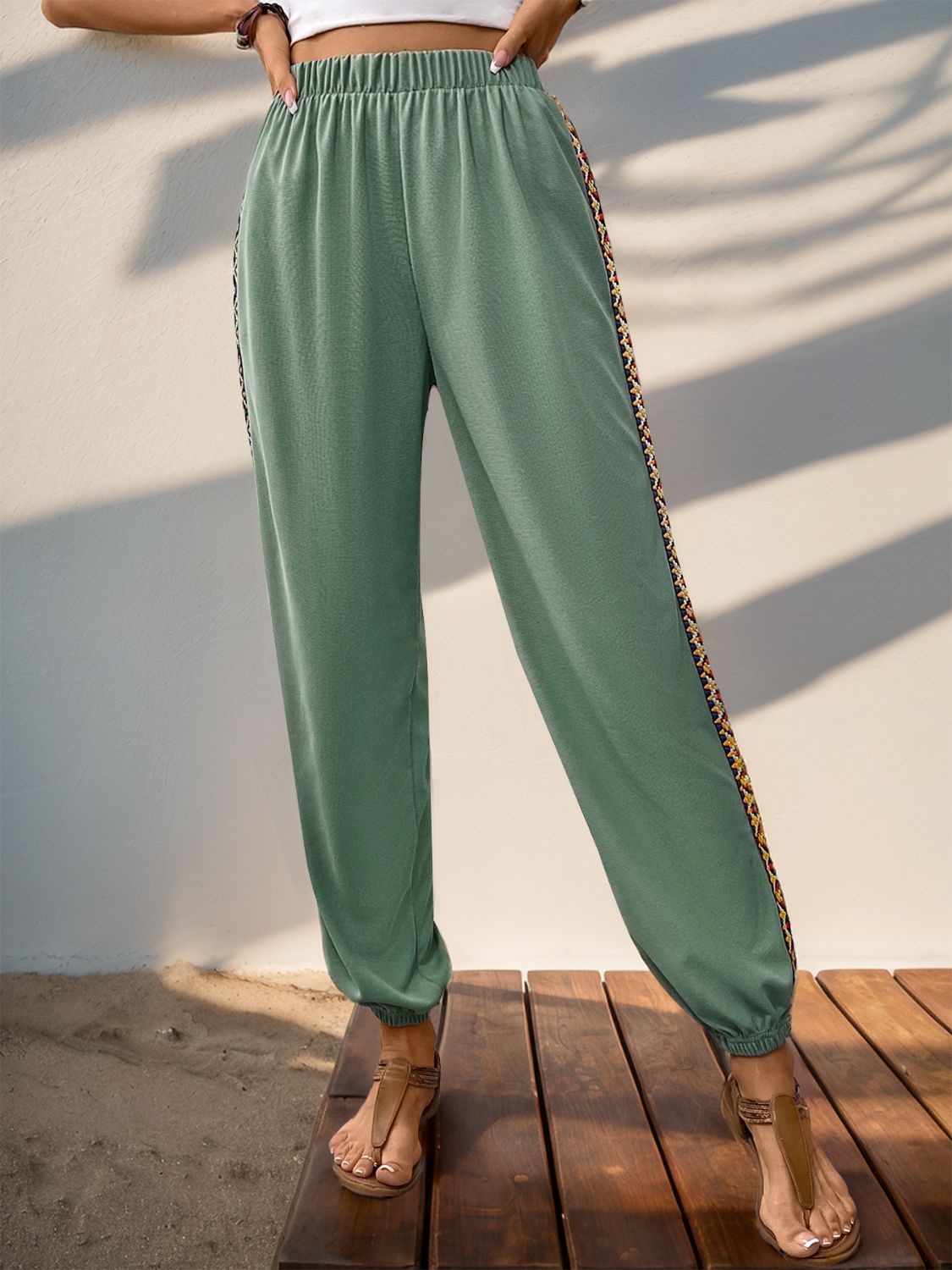 Stylish sage green joggers with elastic waist and colorful side detail.