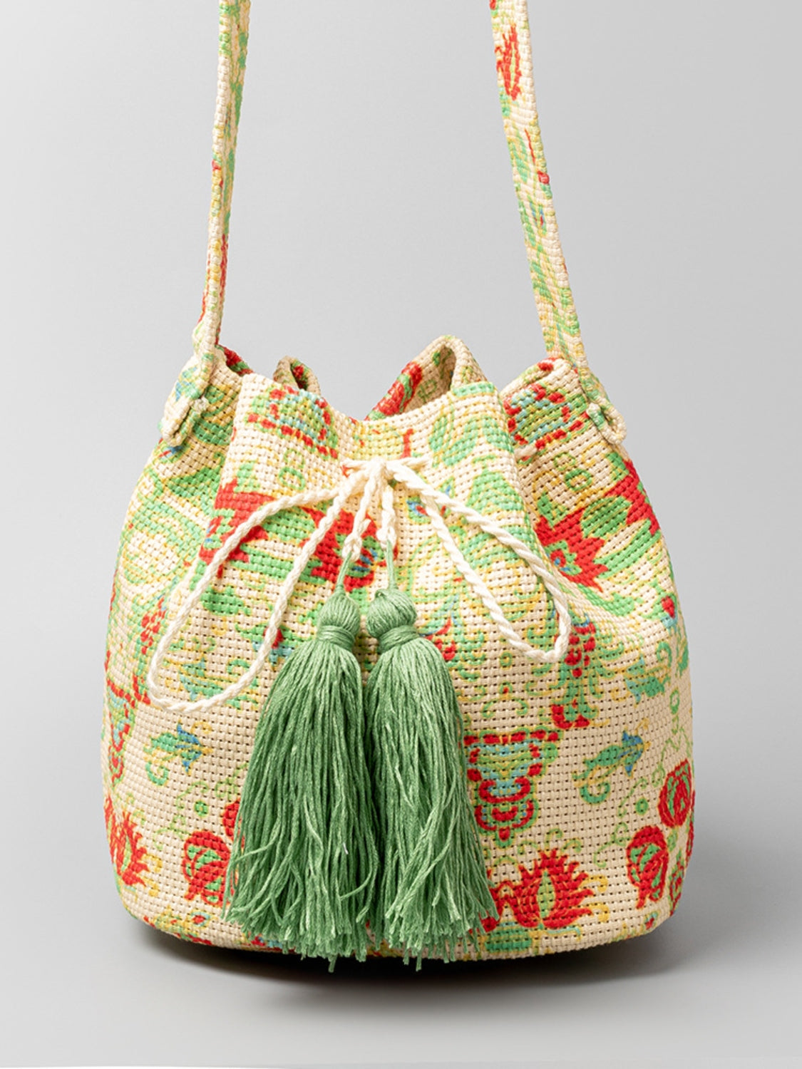 Green and red floral bucket bag with green tassel accents.