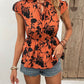 Chic orange floral tie-neck blouse with cap sleeves & a cinched waist, perfect for a summer look that's both stylish and comfortable