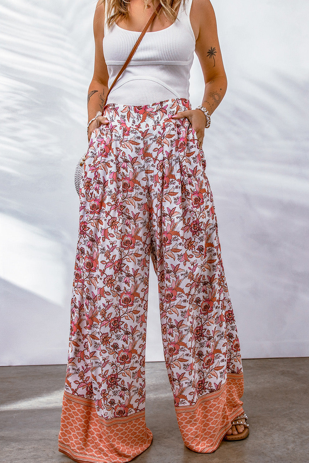 High-waisted palazzo pants with a bold floral pattern and orange hem accents
