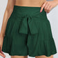 Chic hunter green high-rise shorts with a flattering smocked waistband and tie-front. Perfect for a stylish, comfy summer look.