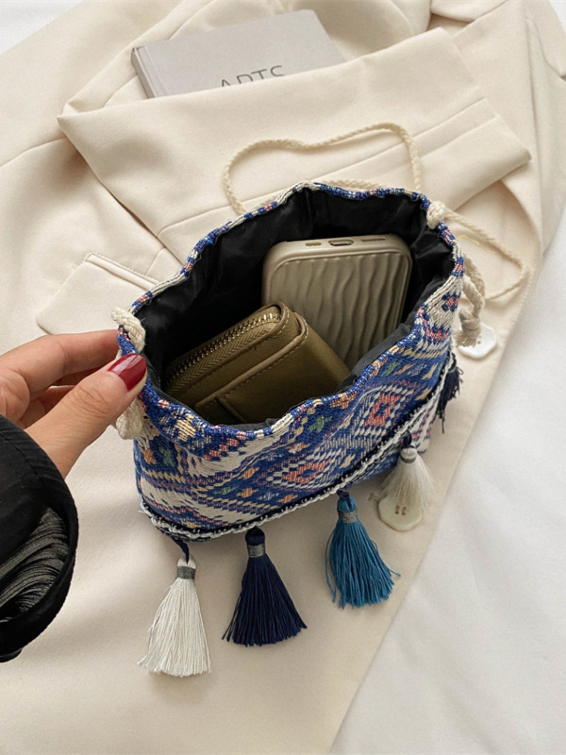 Navy drawstring pouch with intricate geometric design and tassel embellishments.