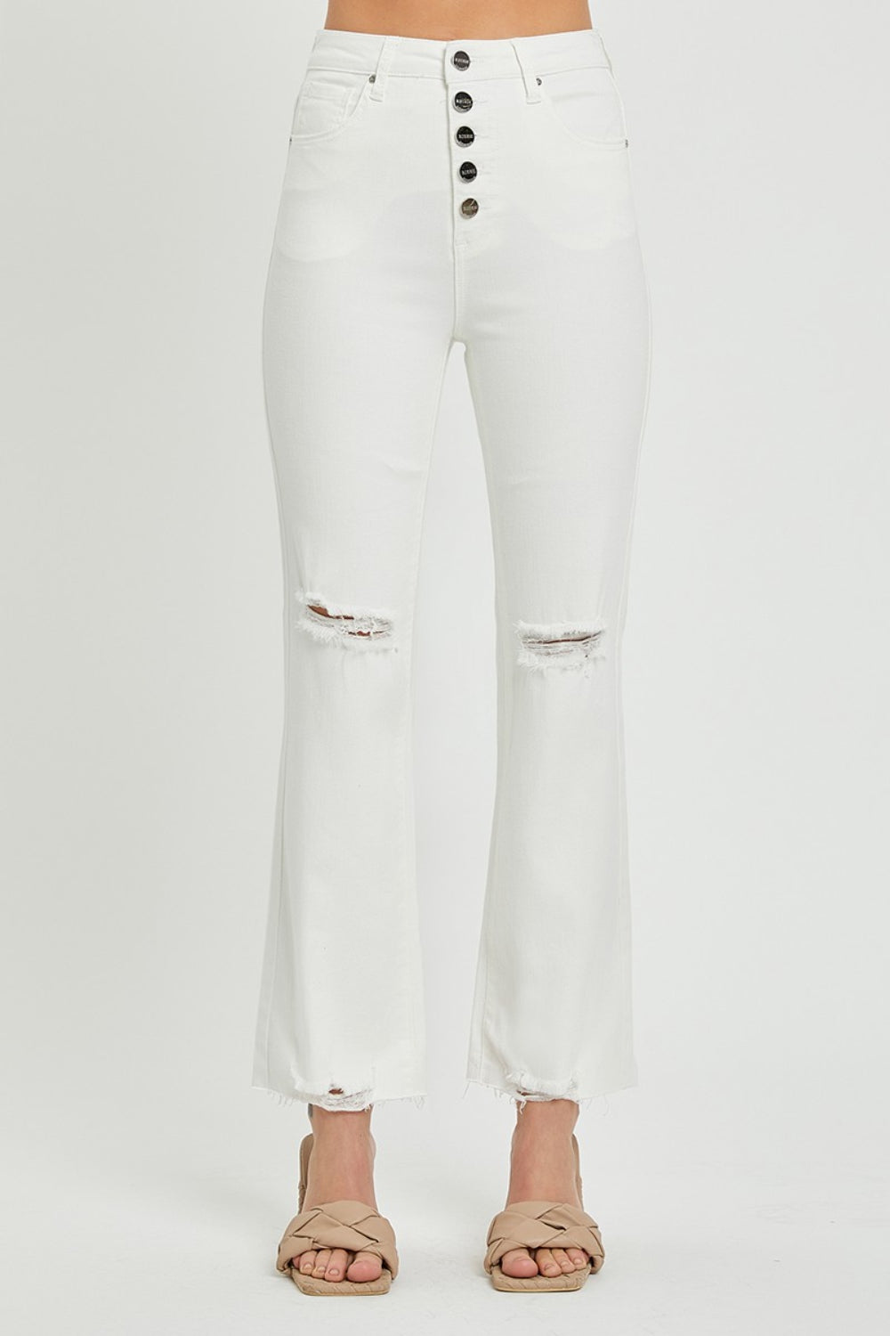 Button fly white jeans with ripped knees and high-waisted fit.