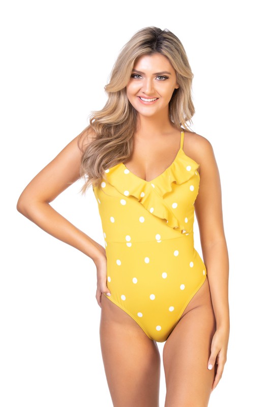 Woman in a trendy yellow polka dot swimsuit with adjustable straps and a bow tie back, ready for a sunny day at the beach.