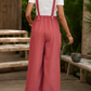 Back view of woman in red bohemian overalls, showing adjustable straps and wide-leg fit.