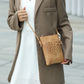 Beige crossbody bag with intricate heart cutout and long strap