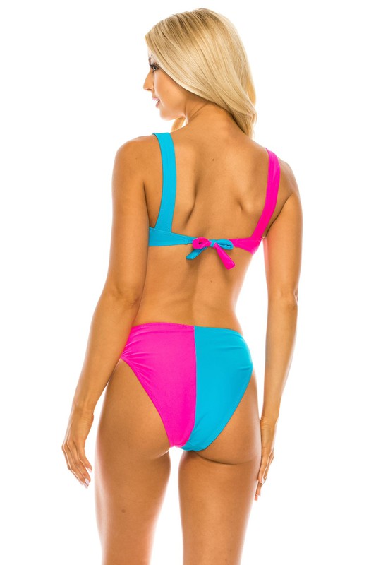 Back view of a woman in a two-piece color block bikini, showing the adjustable tie closure and wide supportive straps.