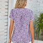 Notched neck blouse in a purple floral pattern with short sleeves