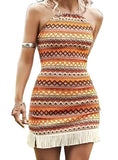 Colorful Aztec print halter neck mini dress with fringe hem detail on a woman standing near a white fence in a green field.